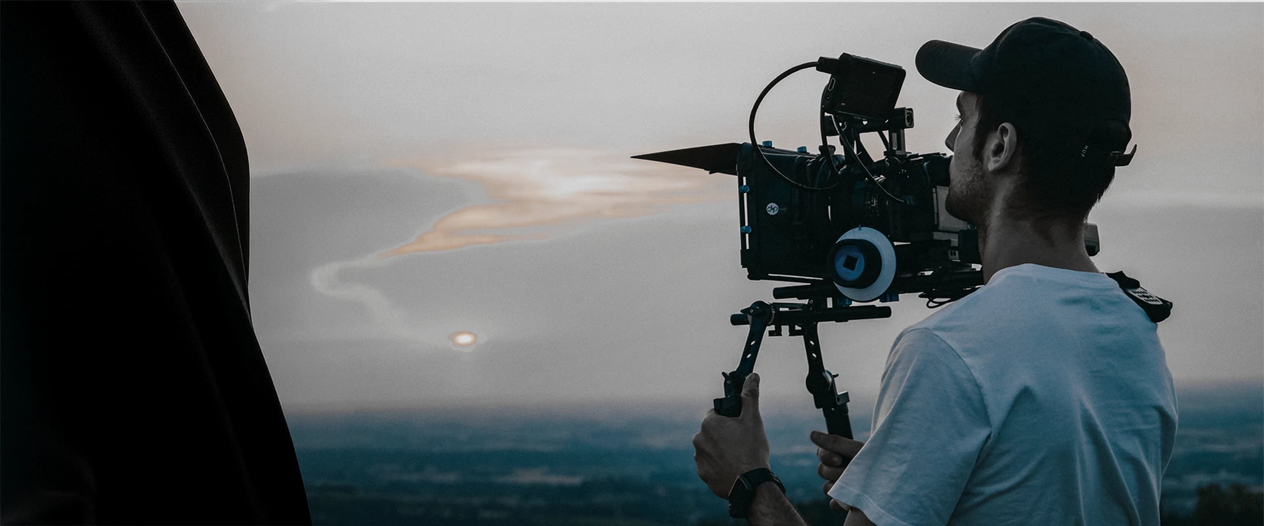 Camera operator filming outdoors at sunset